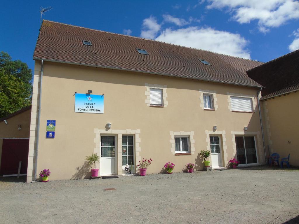 un grande edificio giallo con dei fiori di fronte di l'étoile de la fontchevrière a Neuvy-Saint-Sépulchre