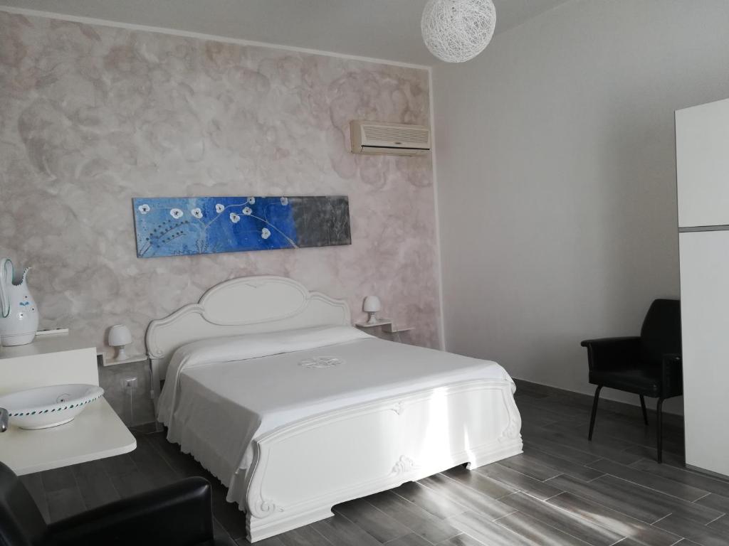 una camera con un letto bianco e una sedia di Il Mandorlo a Platamona