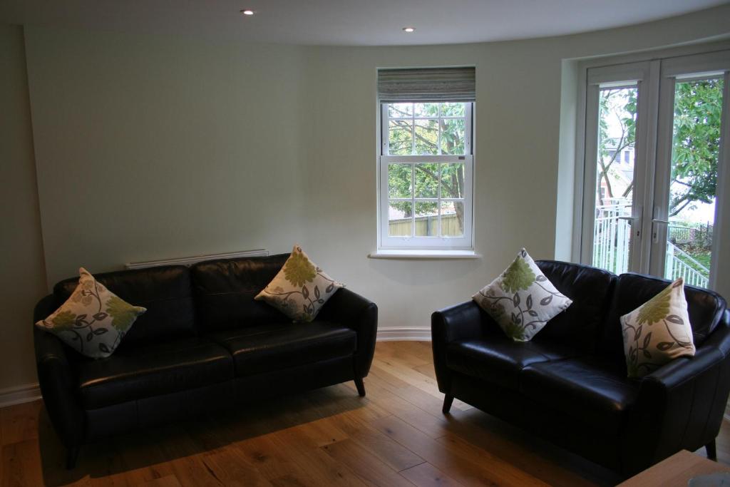sala de estar con 2 sofás de cuero y 2 ventanas en Highlands Apartment 2, en Shanklin