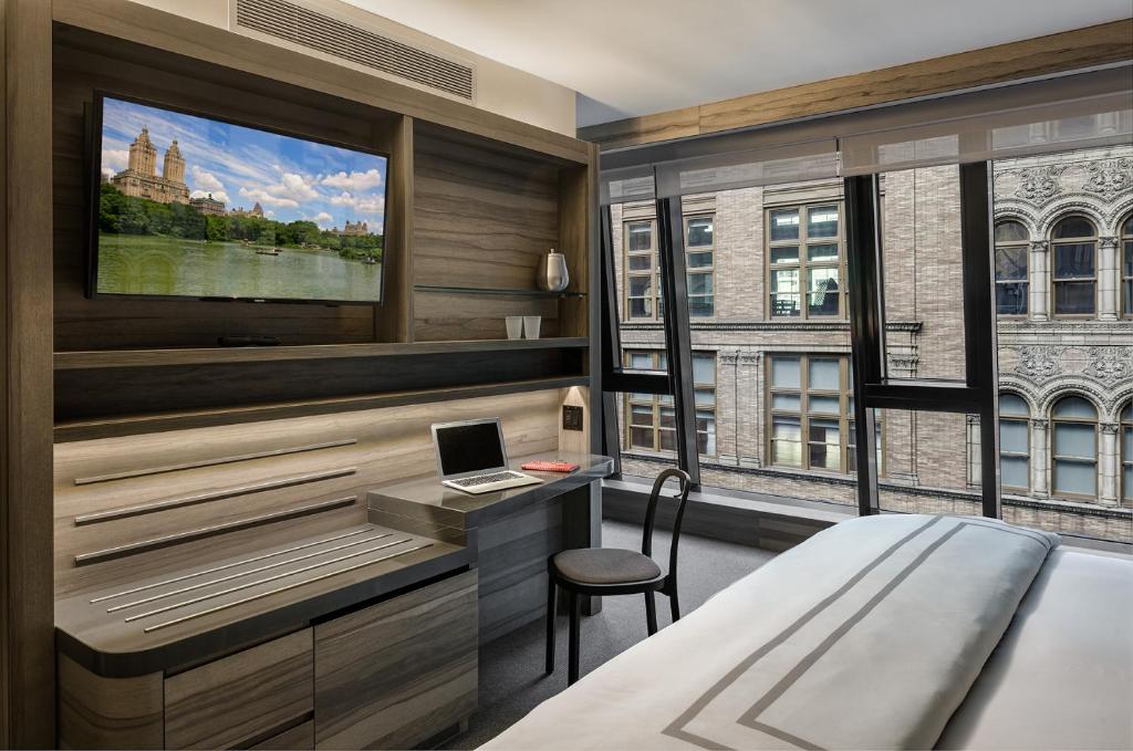 a bedroom with a bed and a desk with a laptop at Carnegie Hotel in New York