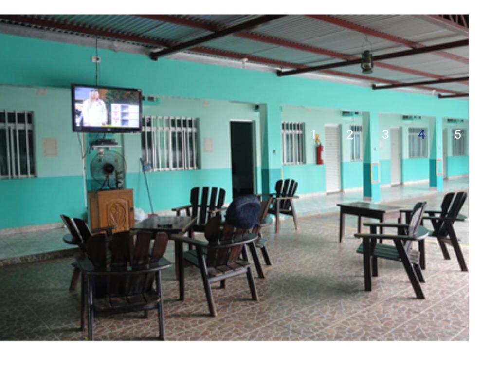 Habitación con mesas, sillas y TV. en Hotel Darcisbel, en Cacoal