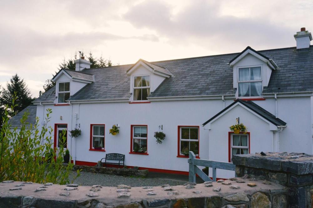 una casa blanca con techo negro en The Old School House en Clifden