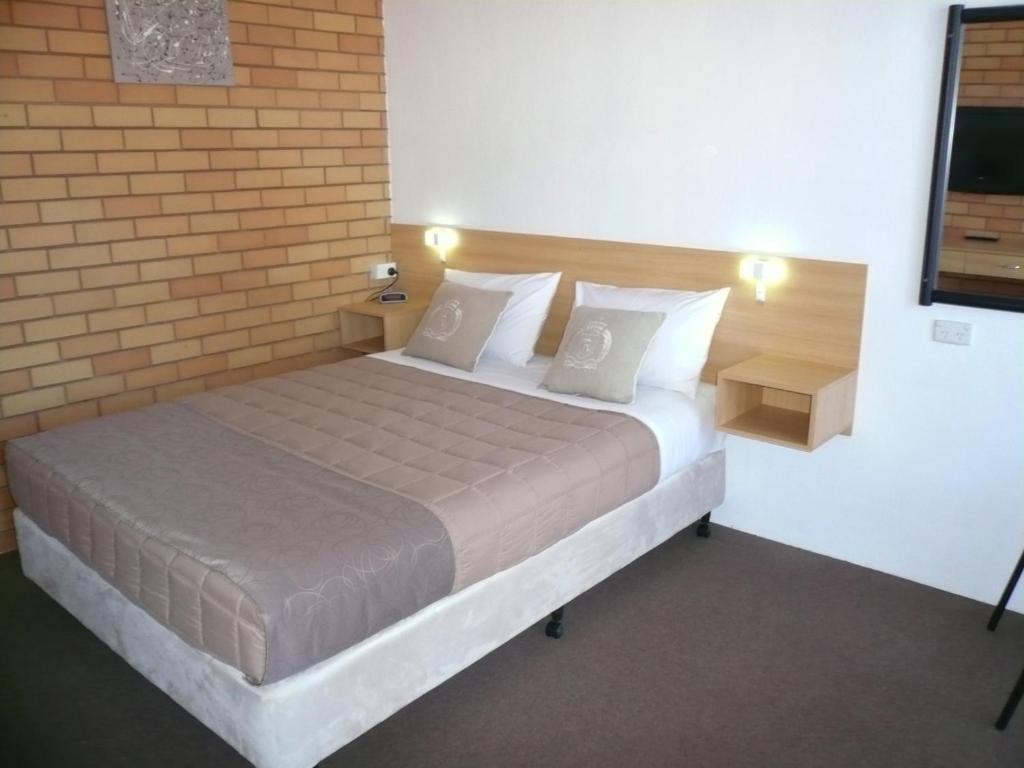 1 dormitorio con cama y pared de ladrillo en Grong Grong Motor Inn, en Grong Grong