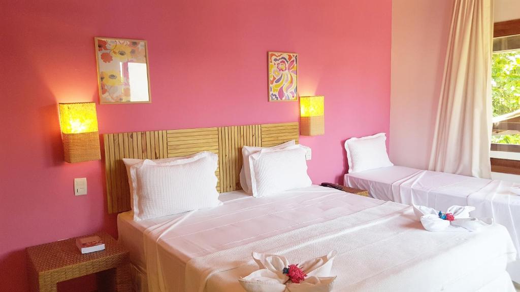 two beds in a room with pink walls at Pousada Paraíso do Forte in Praia do Forte