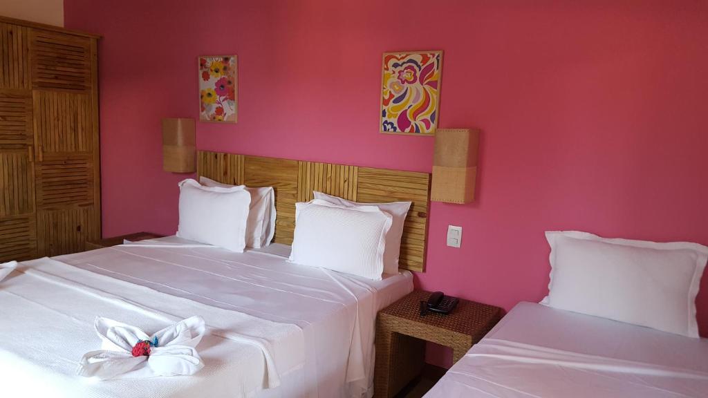two beds in a room with pink walls at Pousada Paraíso do Forte in Praia do Forte
