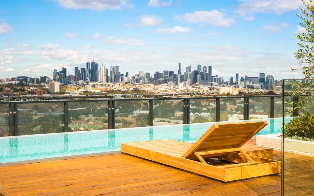a lounge chair on a roof with a view of the city at Quest Flemington Central in Melbourne