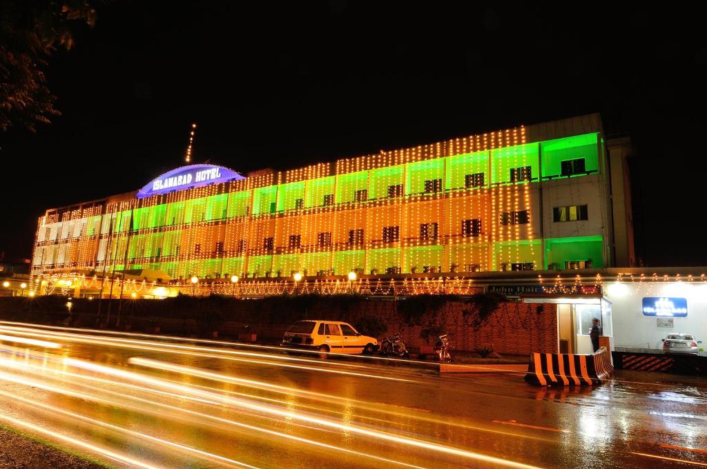 a building is lit up with green and yellow lights at Islamabad Hotel in Islamabad