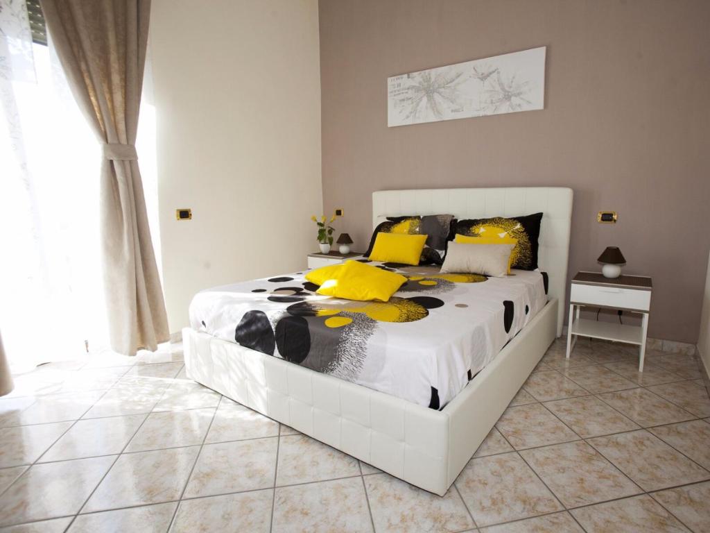 ein Schlafzimmer mit einem großen weißen Bett mit gelben Kissen in der Unterkunft B&B Feni in Pompei