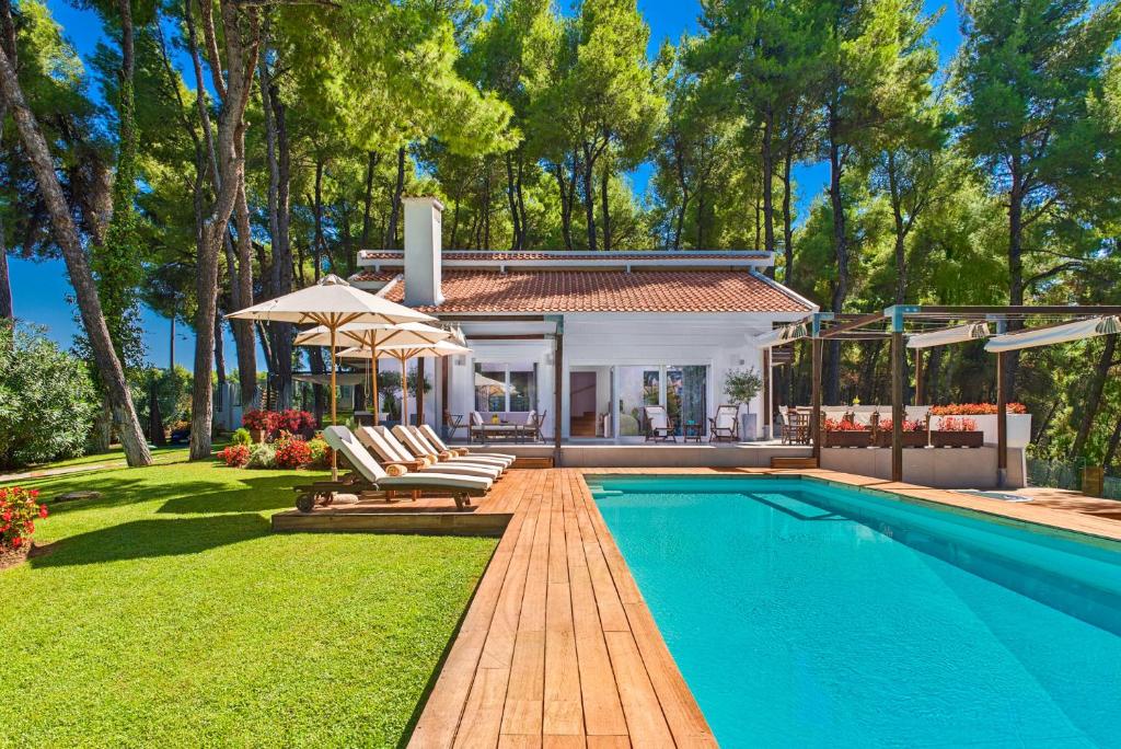 a home with a swimming pool and a house at The White Villa at Sani in Sani Beach