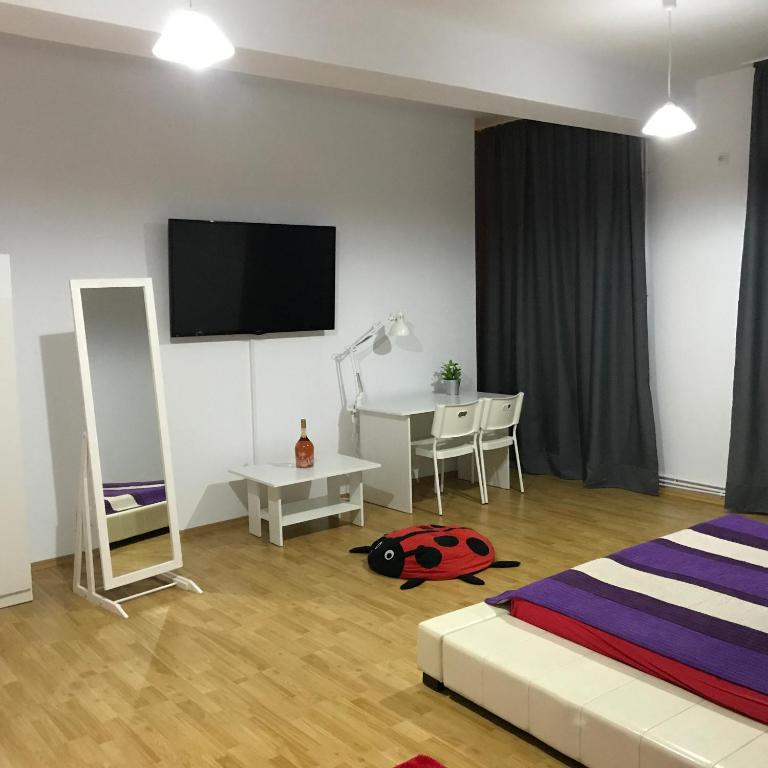 a bedroom with a bed and a desk and a television at Central Park Studios in Bucharest