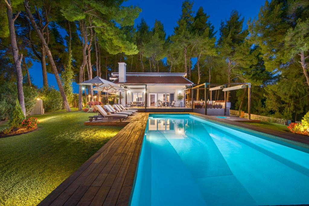 a swimming pool in front of a house at The White Villa at Sani in Sani Beach