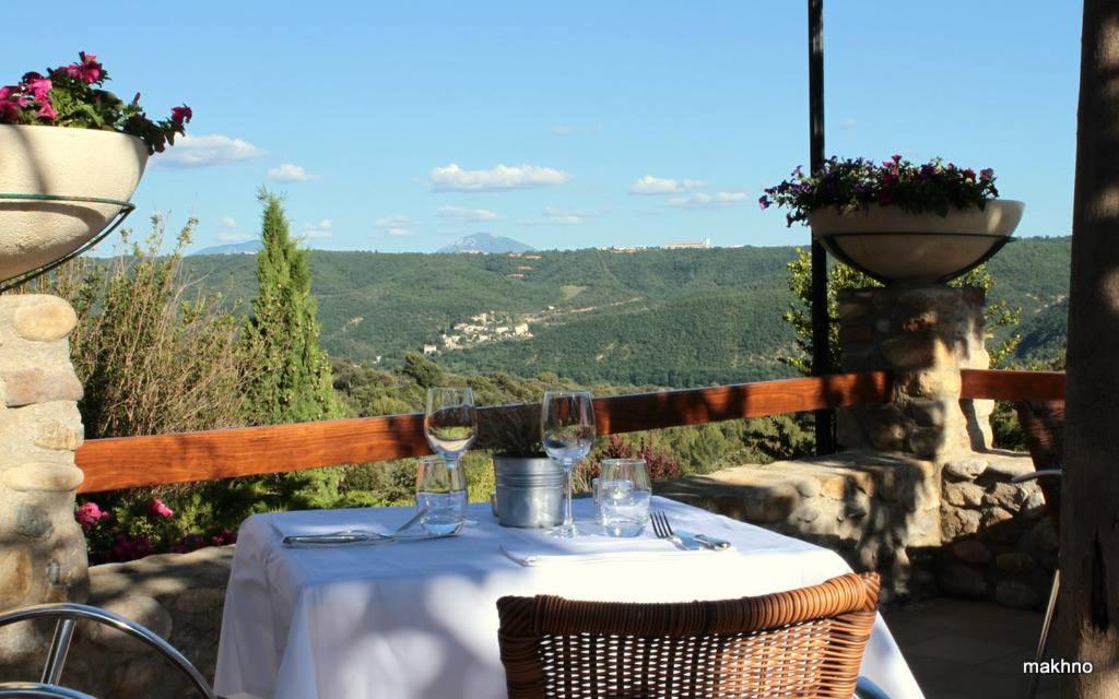 a table with wine glasses on a balcony with a view at La Campagne de Petre in Entrevennes