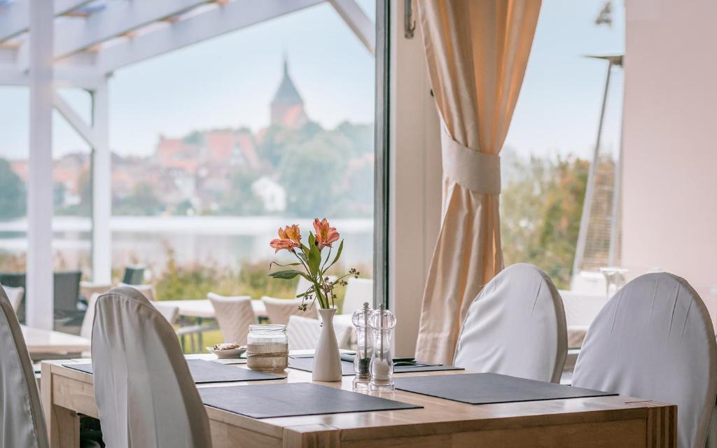 a wooden table with white chairs and a large window at Seehotel Schwanenhof in Mölln