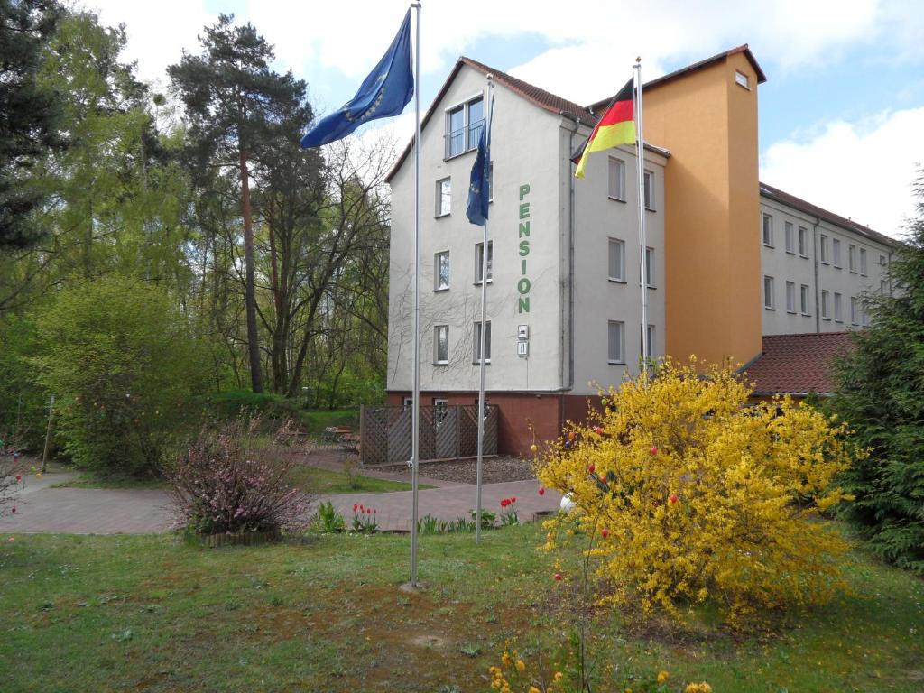 un bâtiment avec deux drapeaux devant lui dans l'établissement Landguthotel Hotel-Pension Sperlingshof, à Dallgow