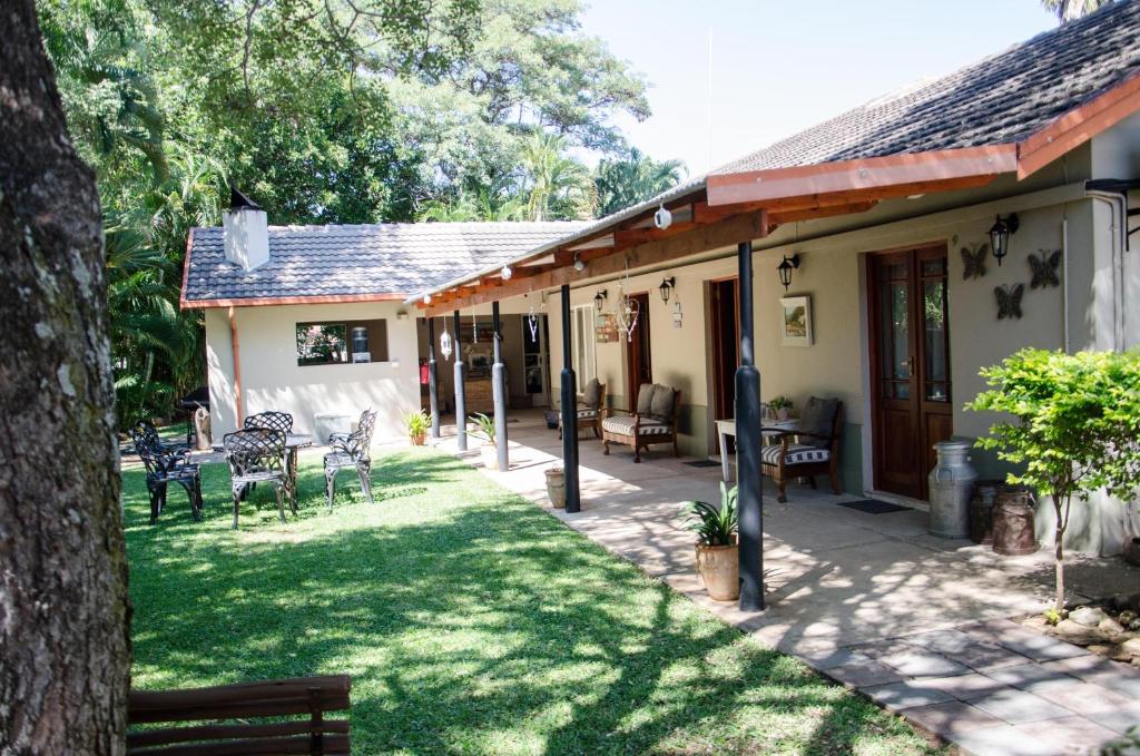Four Seasons Guesthouses في Lephalale: منزل به ساحة مع كراسي وطاولات