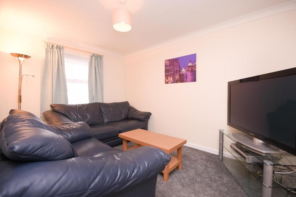 a living room with a leather couch and a flat screen tv at Town or Country - Jessie Terrace House B in Southampton