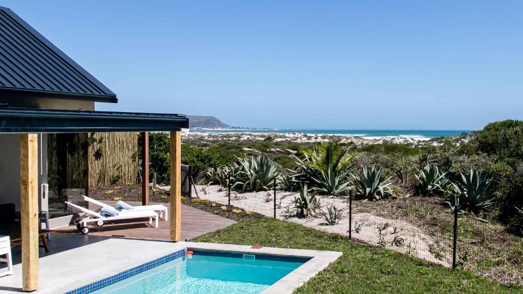 a house with a swimming pool next to the beach at Willow Beach House - with backup power in Noordhoek