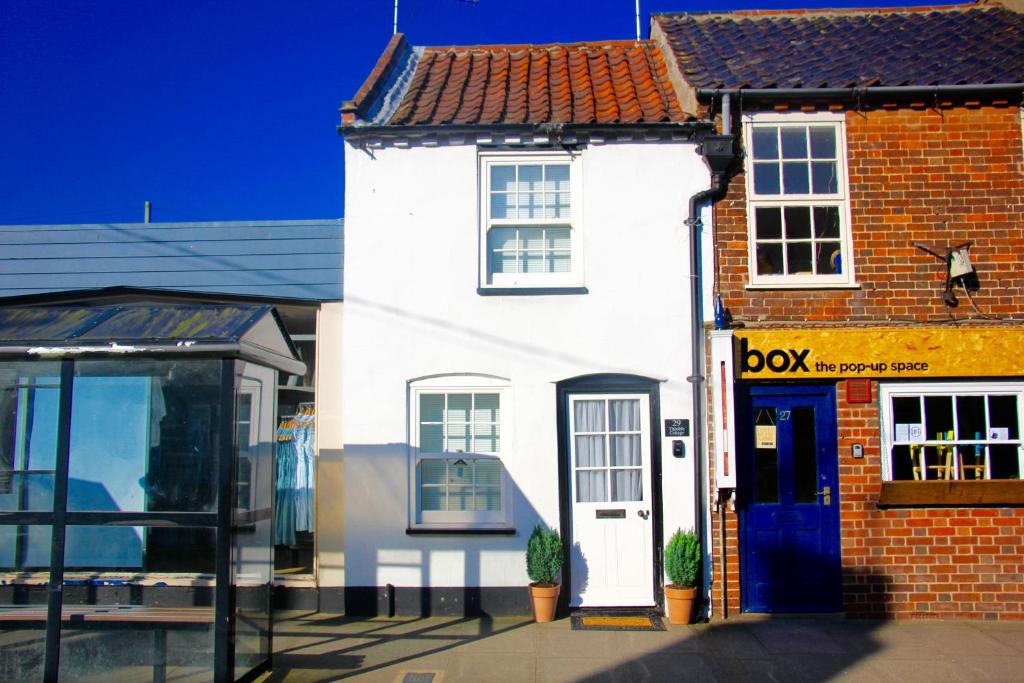 a white building with a blue door on a street at Seaside Fisherman Cottage Southwold in Southwold