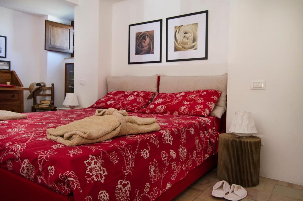 Schlafzimmer mit einem Bett mit einer roten Tagesdecke in der Unterkunft Dimora La Rosa Barocca in Palazzolo Acreide
