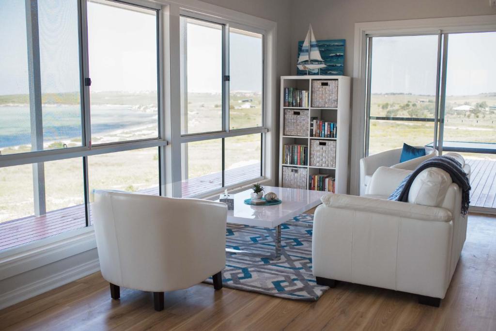 a living room with white chairs and a table and windows at Shades of Blue Eco Retreat in Calca