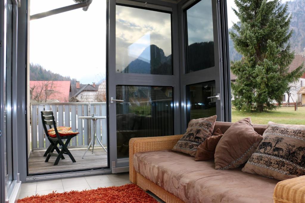 ein Wohnzimmer mit einem Sofa vor einer Glasschiebetür in der Unterkunft Cosy apartment in Kranjska Gora