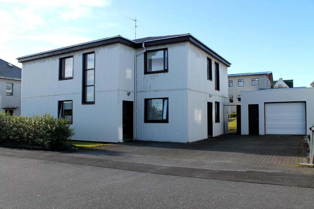una casa blanca con un estacionamiento delante de ella en Reynisstaðir, en Keflavík