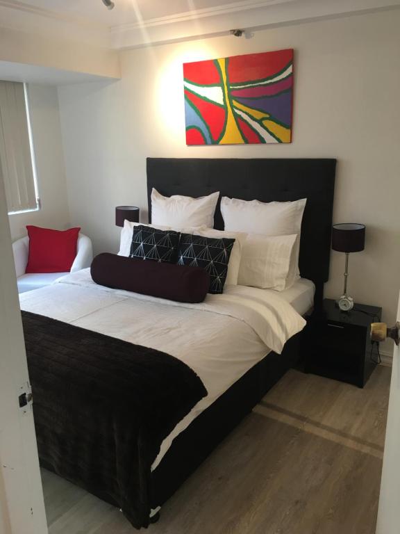 a large bed in a bedroom with a painting on the wall at Sydney City Location in Sydney