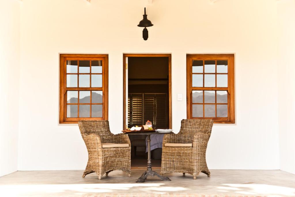 a table and chairs in a room with windows at d'Olyfboom Guest House B & B in Paarl