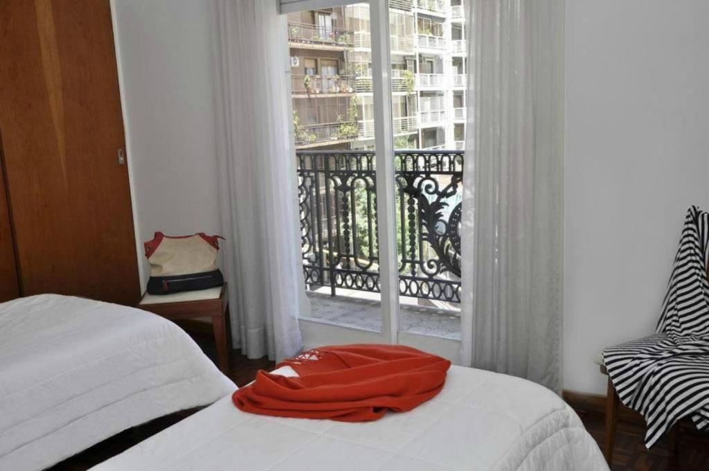 a bed with a red towel on it in front of a window at Petit Recoleta Suites in Buenos Aires