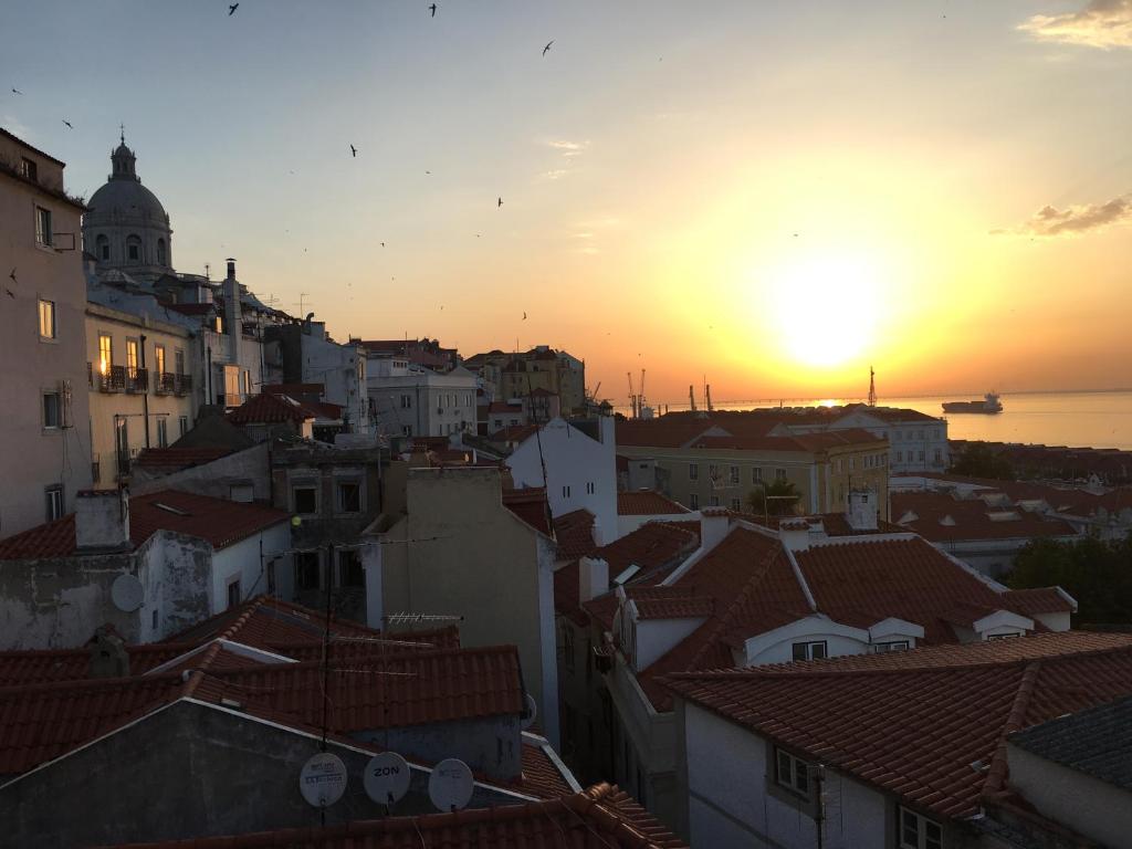 un coucher de soleil sur les toits d'une ville dans l'établissement Typical river view cosy and central, à Lisbonne