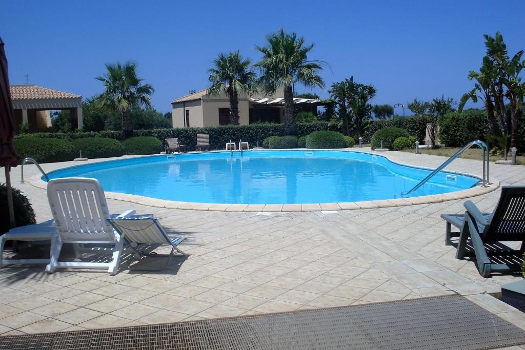 a swimming pool with two lounge chairs next to it at Casa Vacanze Libeccio - Villetta con giardino e piscina condominiale in Custonaci