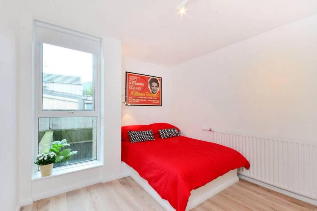 Midtown London Apartment في لندن: غرفة نوم بسرير احمر ونافذة