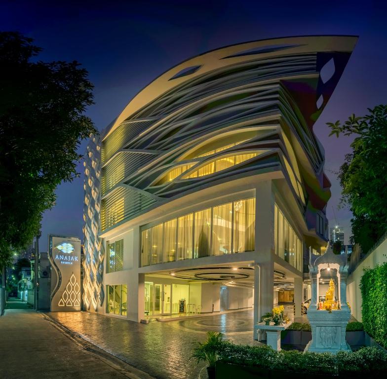 a building with a curved facade at night at Anajak Bangkok Hotel - SHA Plus in Bangkok