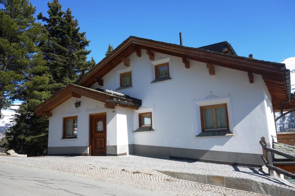 a white house with a wooden door and trees at Chesa il Rifugio 1 in St. Moritz