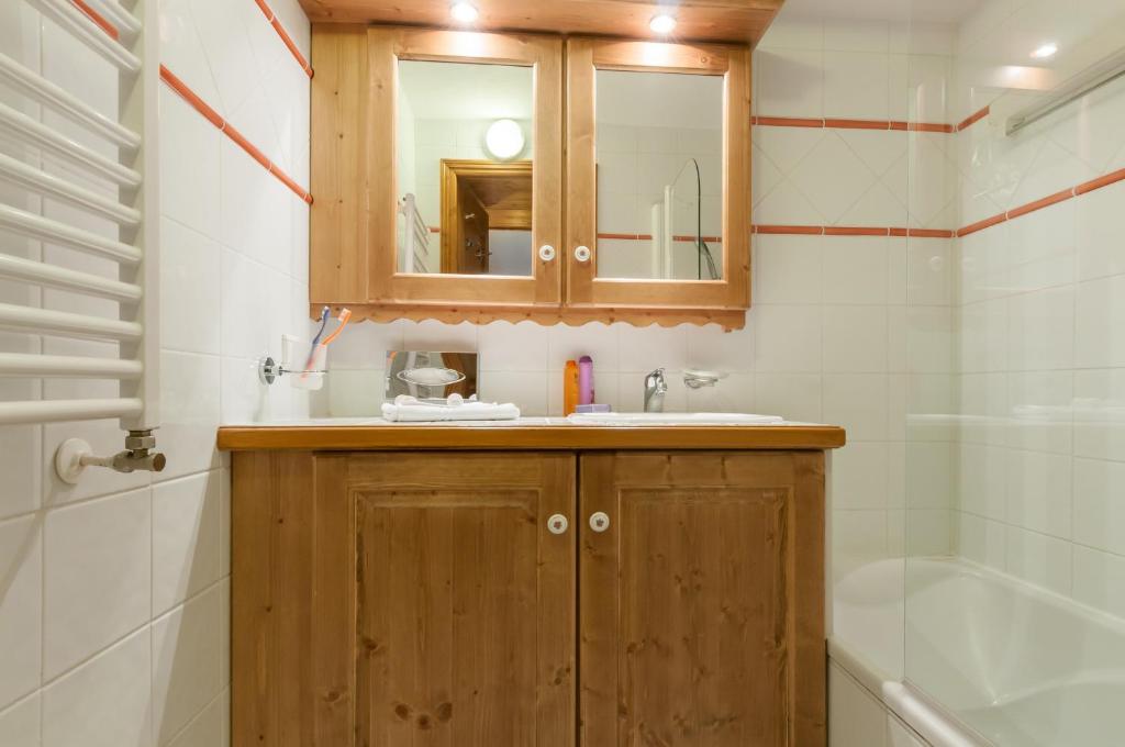 a bathroom with a sink and a mirror and a tub at Résidence Pierre &amp; Vacances Premium Les Alpages de Chantel in Arc 1800