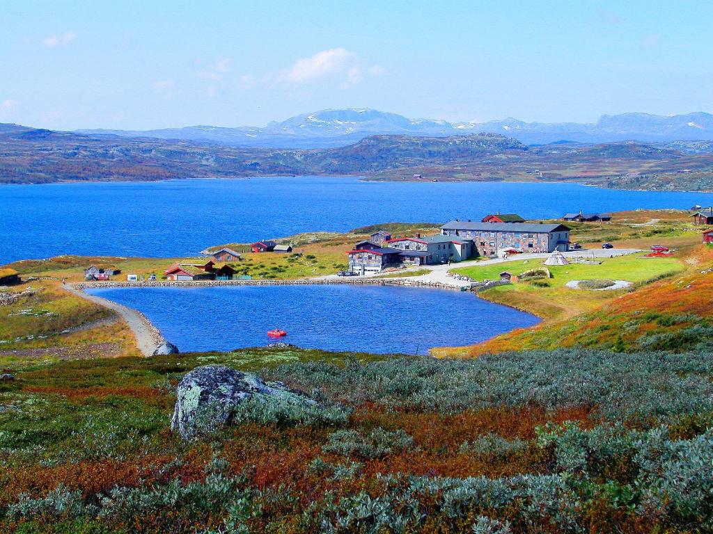 a lake in the middle of a field with houses at Rødungstøl Høyfjellshotell in Rødungstøl