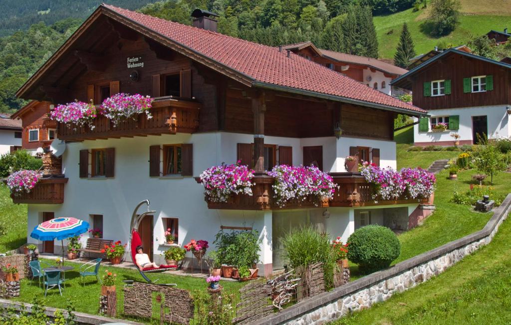 une maison dans les montagnes avec des fleurs sur les balcons dans l'établissement Ferienwohnung Winkler, à Silbertal