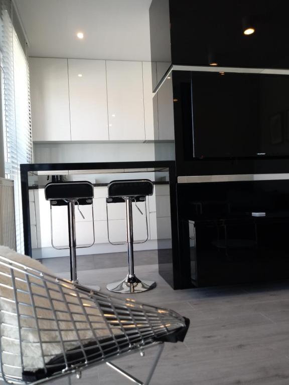 a kitchen with two bar stools and a television at Apartament na Złotej in Kielce