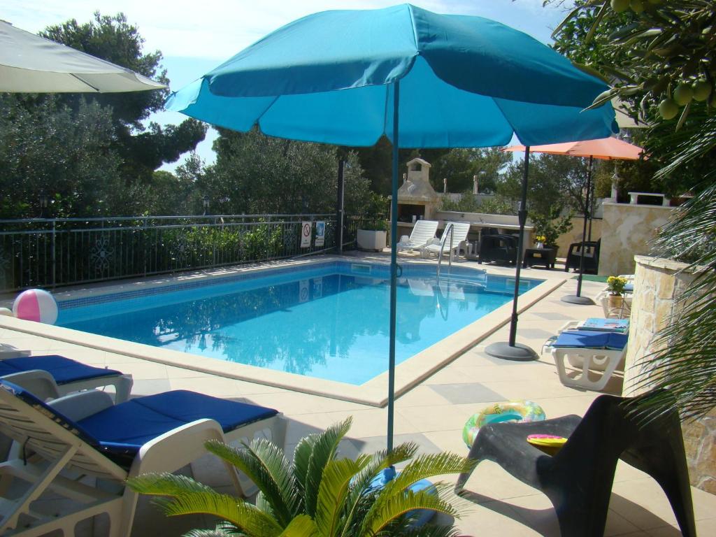 uma piscina com dois guarda-sóis e duas cadeiras e uma piscina em Apartments Žgogo em Trogir