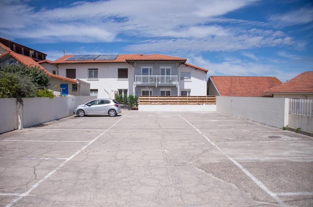 a car parked in a parking lot in front of a house at Hotel Atlantique in Mimizan-Plage