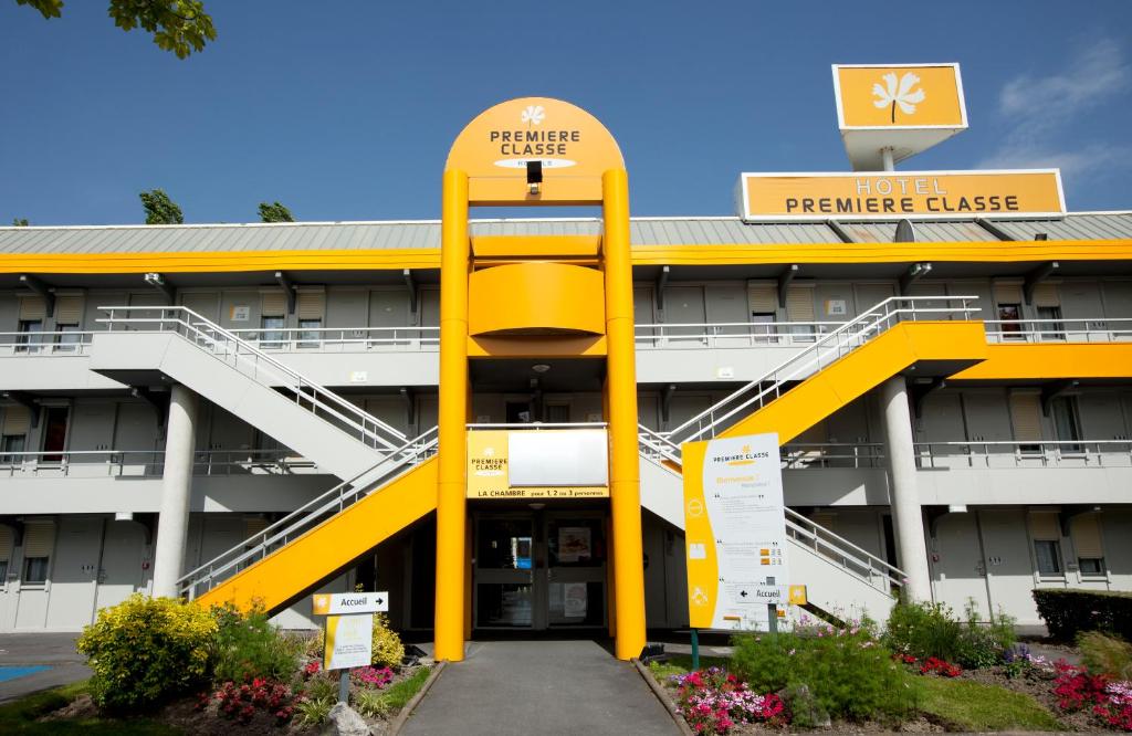 a large building with a yellow sign in front of it at Premiere Classe Versailles - Saint Cyr L'ecole in Saint-Cyr-lʼÉcole