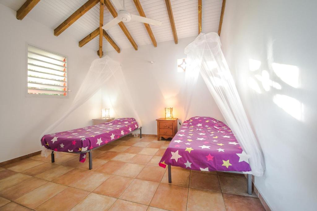 a room with two beds with purple sheets at Sunset Surf Camp in Saint-François