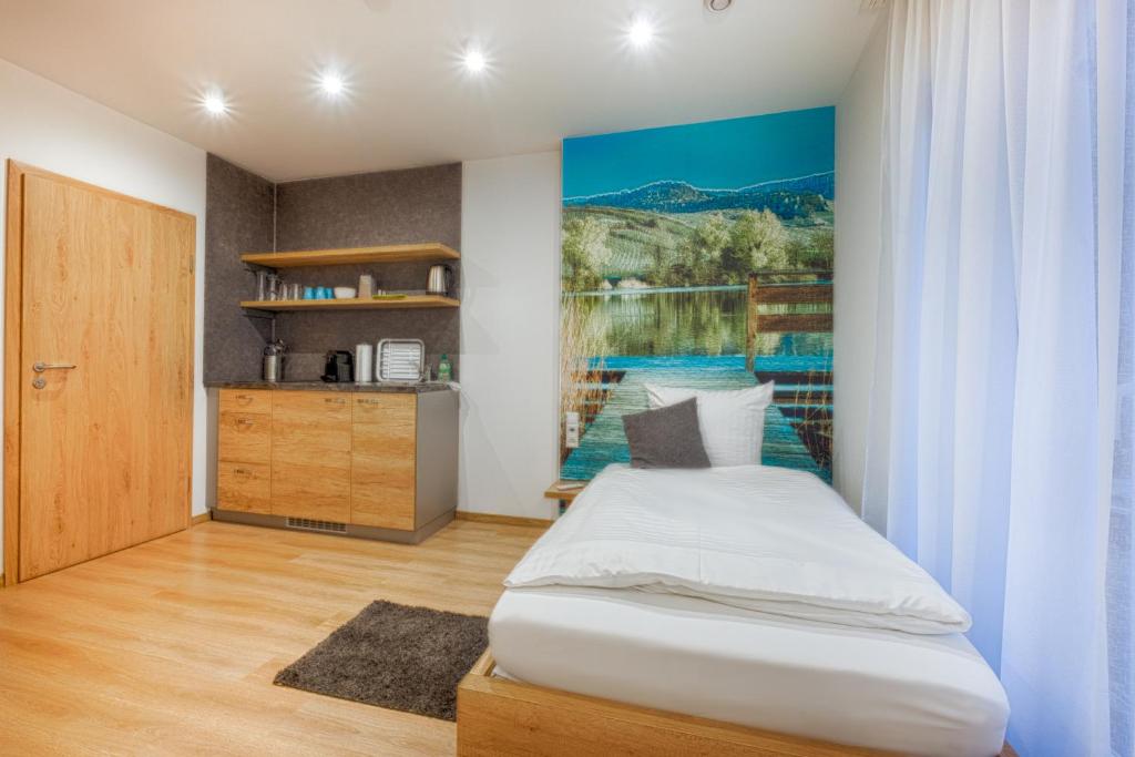 1 dormitorio con 1 cama y una pintura en la pared en Pension Breitenauer See en Hößlinsülz