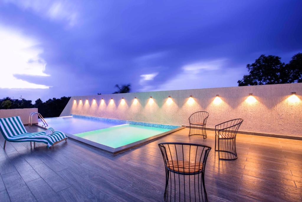 a patio with chairs and a swimming pool at night at Sidra Pristine Hotel and Portico Halls in Cochin