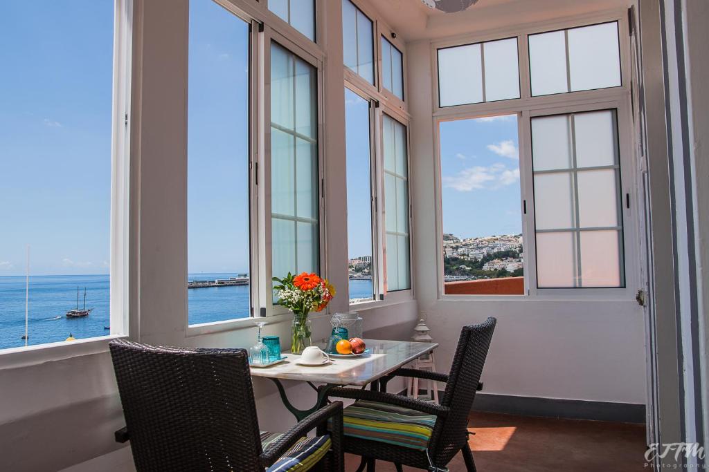 een eetkamer met een tafel, stoelen en ramen bij Vitorina Corte Guesthouse in Funchal