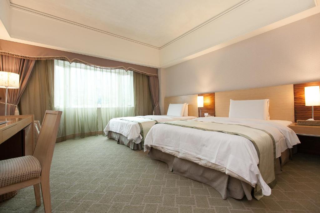 a hotel room with two beds and a window at Hoya Hot Springs Resort &amp; Spa in Wenquan
