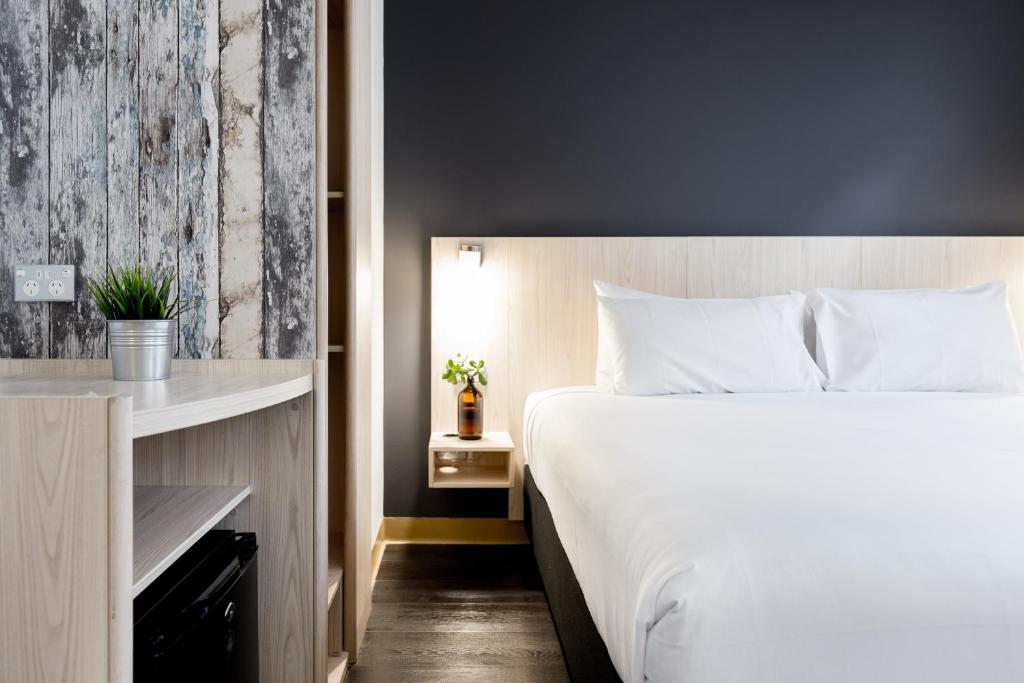 ein Schlafzimmer mit einem großen weißen Bett und einem Tisch in der Unterkunft ibis Sydney Barangaroo in Sydney