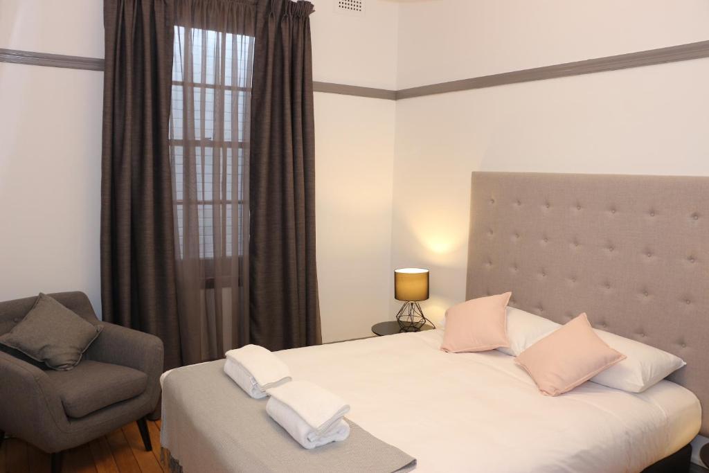 een slaapkamer met een bed, een stoel en een raam bij Guildford Hotel in Guildford