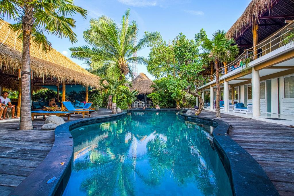 a swimming pool in a resort with palm trees at The Green Room Seminyak in Seminyak