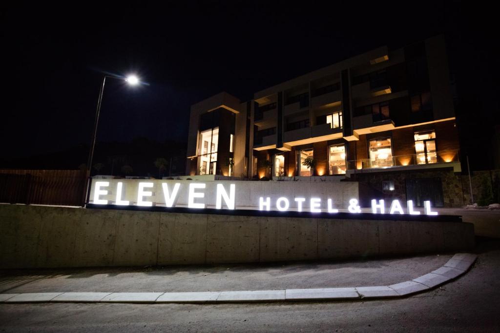 a building with a sign that reads eleven hotel and hall at night at Eleven Hotel and Hall in Almaty